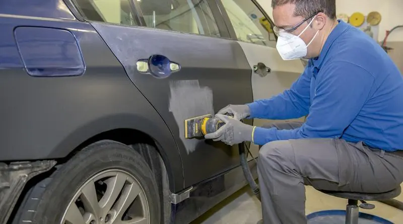 Technician sanding a repaired body panel