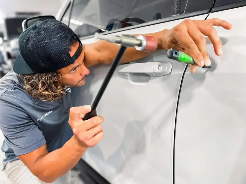 Technician removing a dent from a white door